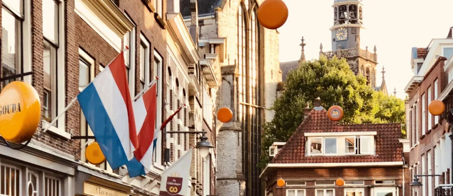 A historic Dutch street with traditional houses and a church tower.