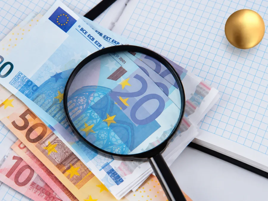 Euro banknotları ve hesap belgeleri üzerinde büyüteç.